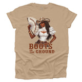Tan t-shirt with a graphic of a woman in a cowboy hat holding a fan, with text 'WHERE THEM FANS AT' and 'BOOTS ON THE GROUND'.